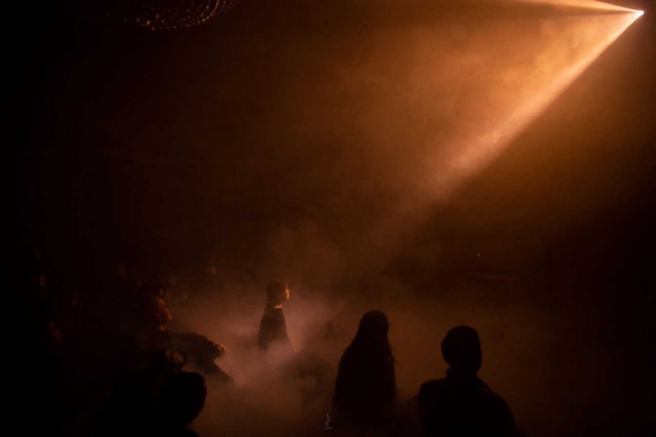 A light beams shines on an attentive listener sitting in a sea of fog during Lihla and Ray Tseng's performance »Dragonfly« at XAOS Festival 2025 in Ulaanbataar